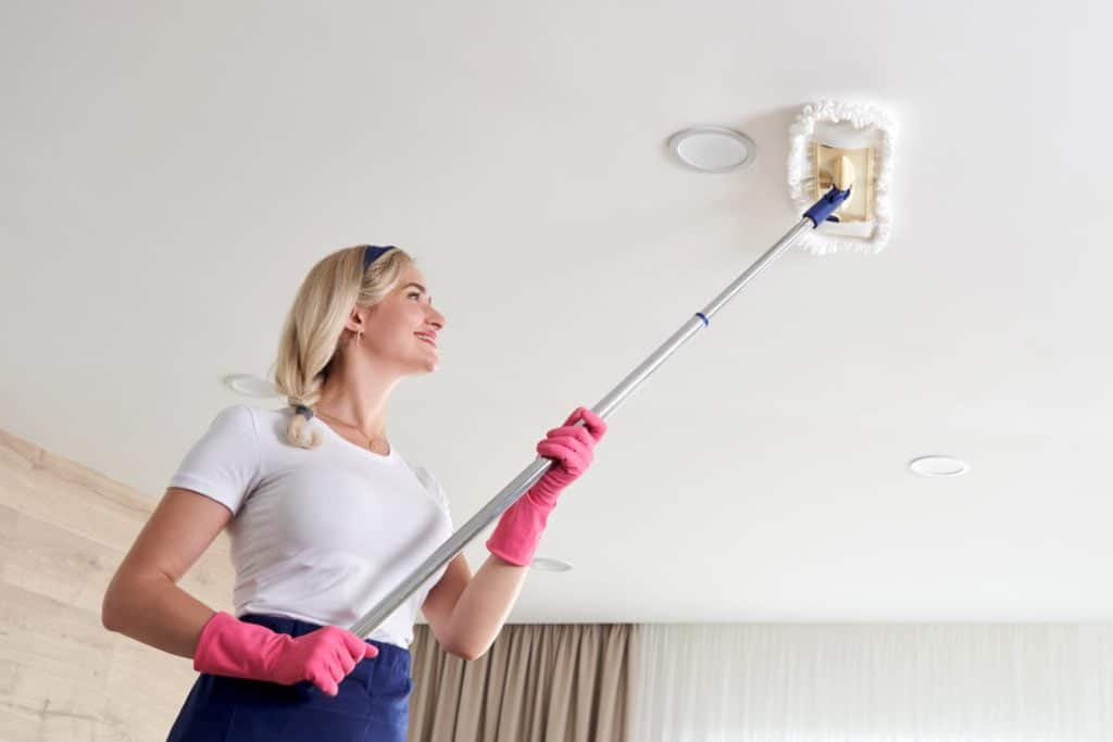 A female cleaning her ceiling before paint application