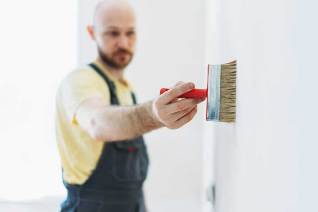 A man applying primer to a wall